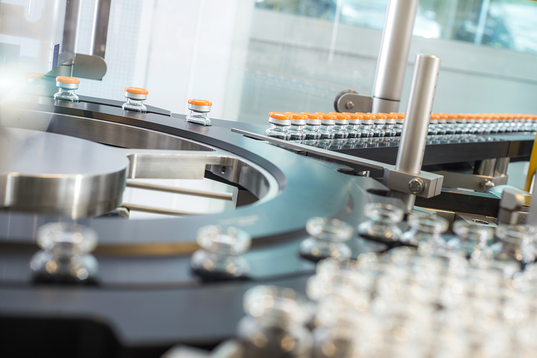 Automatisierte ROTOP-Anlage im Reinraum mit bereits verkrimpten Vials auf dem Förderband bei der GMP-konformen Herstellung von Cold Kits